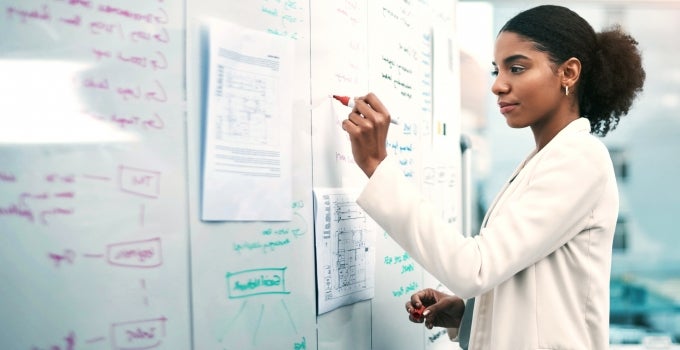 Black female PhD student writing on white board