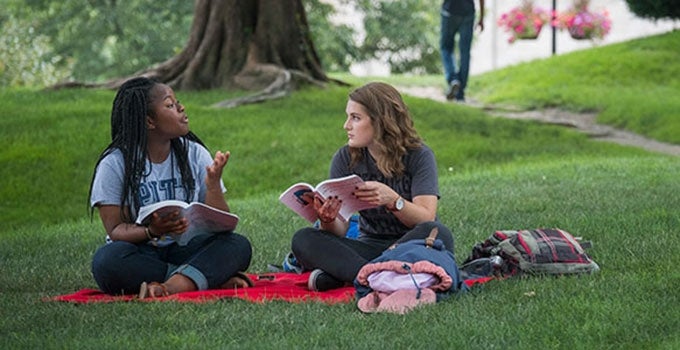 two Pitt students studying on green lawn